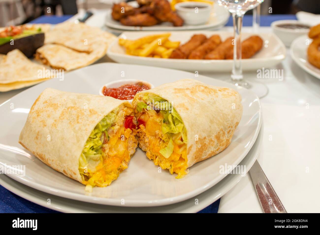 Maistortilla Burrito mit Hühnerfleisch, Salat und Tomaten mit Cheddar-Käse Stockfoto