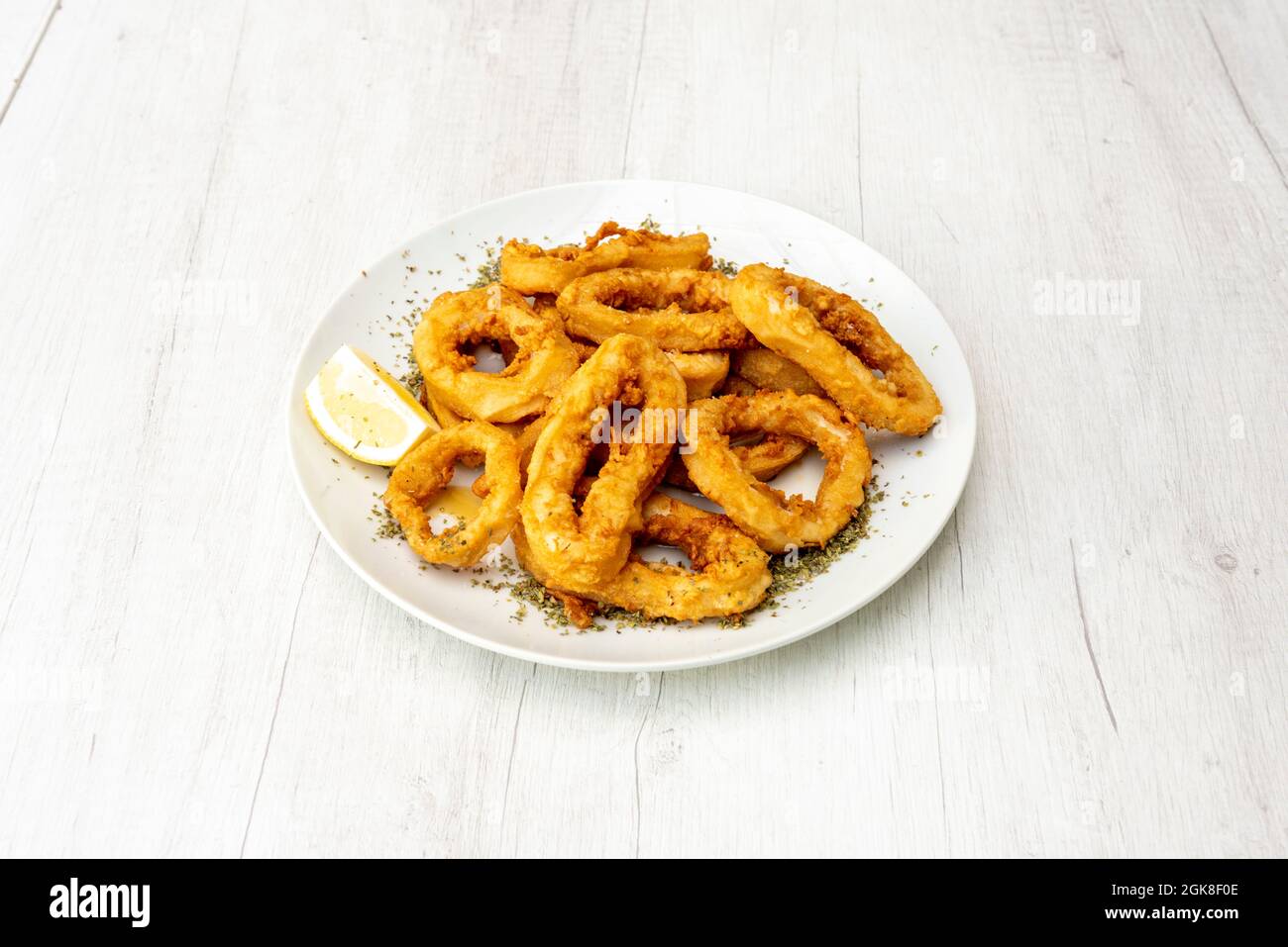 Servieren von andalusischem Tintenfisch mit Zitrone und Oregano auf weißem Holztisch Stockfoto