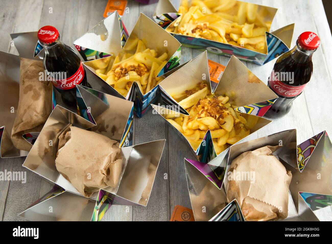 Dnepropetrovsk, Ukraine - 08.05.2021: Verschiedene Speisen zum Mitnehmen auf dem Küchentisch. Pommes Frites, Cola-Flaschen und ein verpackter Hot Dog. Nahaufnahme, oben vi Stockfoto