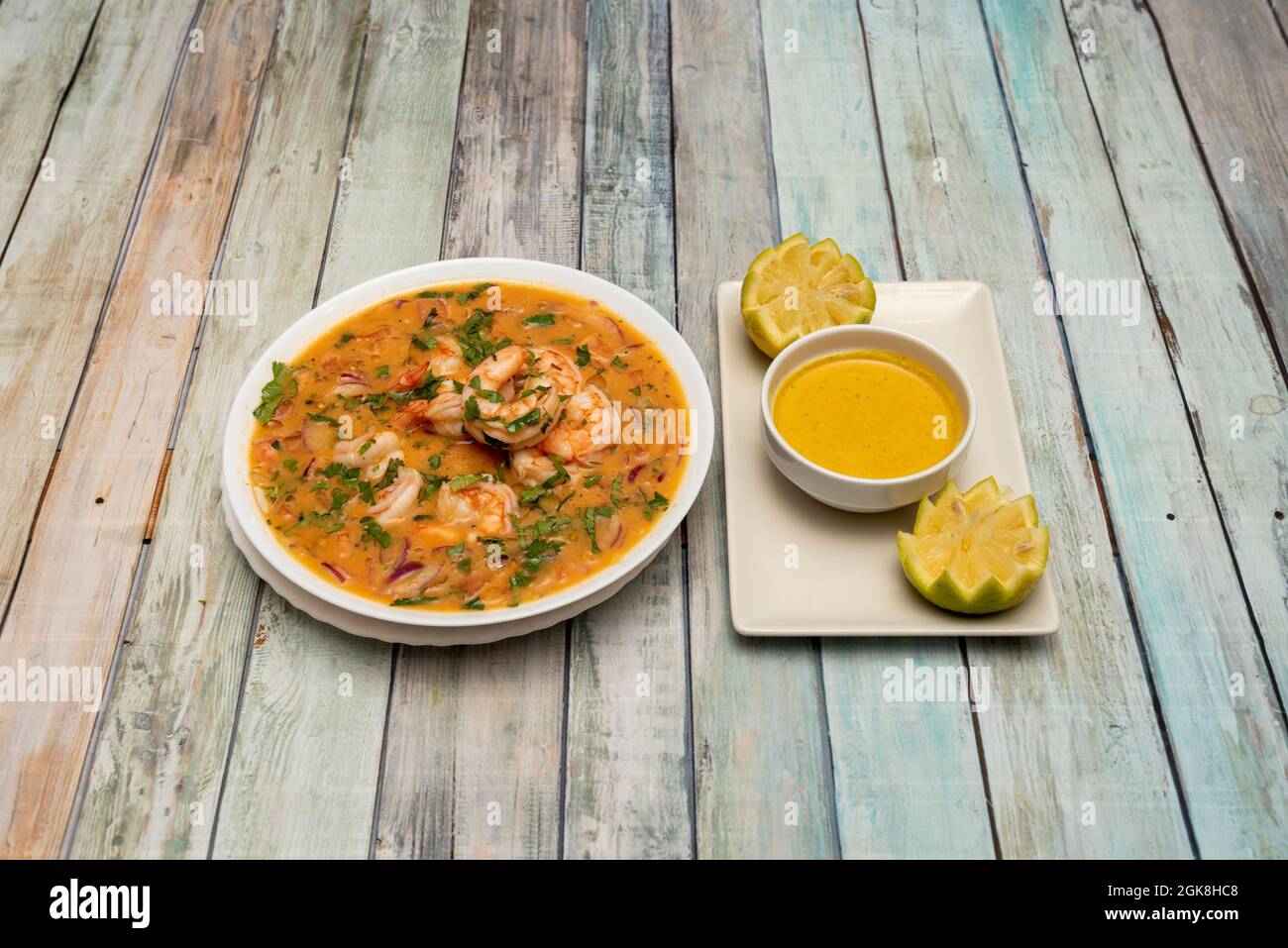 Großzügige Portion Shrimp Ceviche mit Petersilie, viel Marinade-Sauce und Zitronen auf weißen Tellern Stockfoto