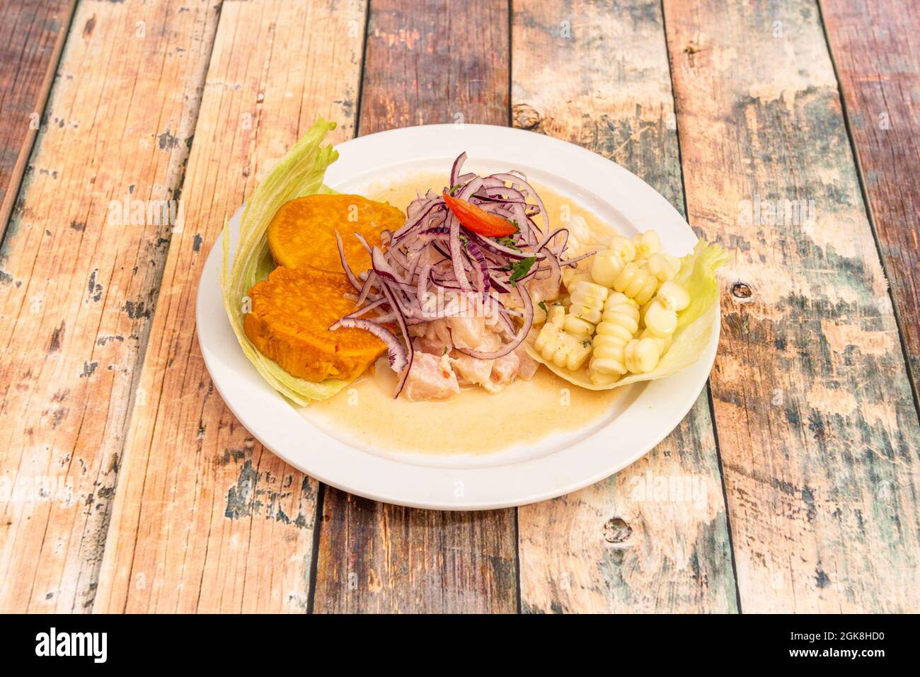 Peruanische corvina Ceviche-Ration mit Süßkartoffelscheiben und Maiskörnern auf einem weißen Teller Stockfoto