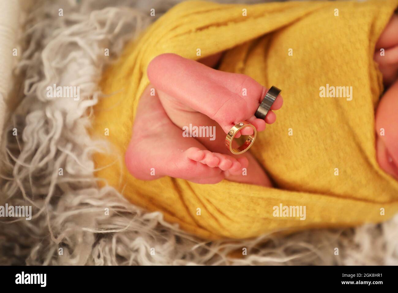 Nahaufnahme der Füße eines neugeborenen Jungen mit Ringen in Zeh und Finger, friedliches Gesundheitskonzept Stockfoto