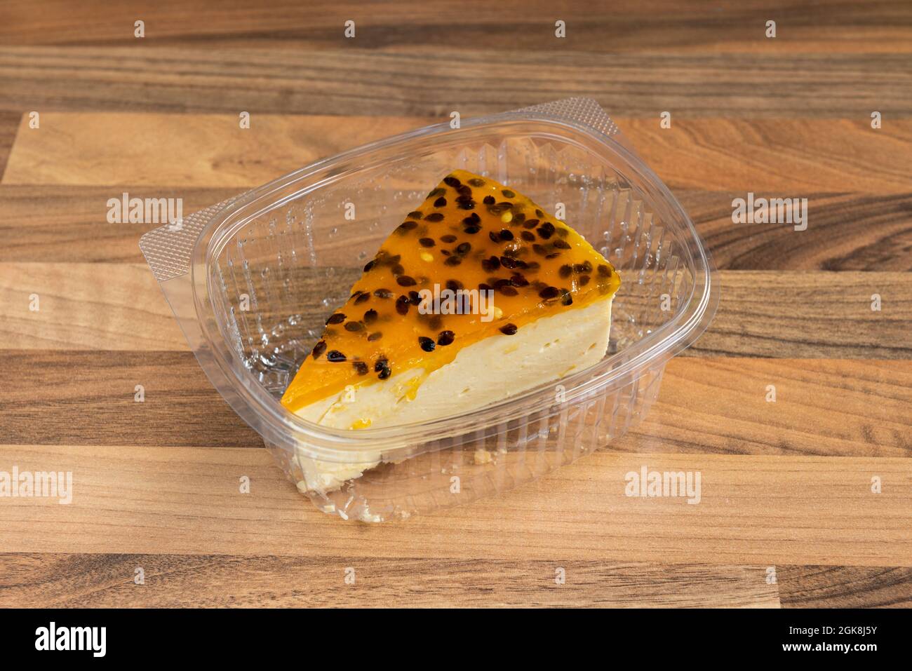Portion Passionsfrucht-Käsekuchen im Container für die Lieferung nach Hause auf Holztisch Stockfoto