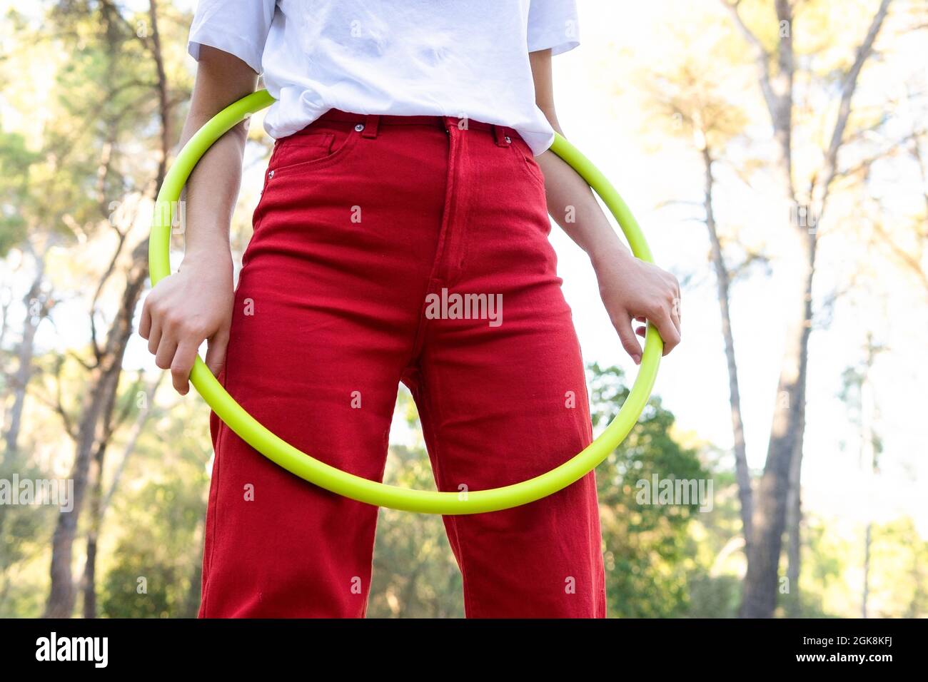 Von unten der Ernte unkenntlich weibliche Teenager in roten Jeans wirbeln Hula Hoop Reifen während mit Freizeit im Park Stockfoto