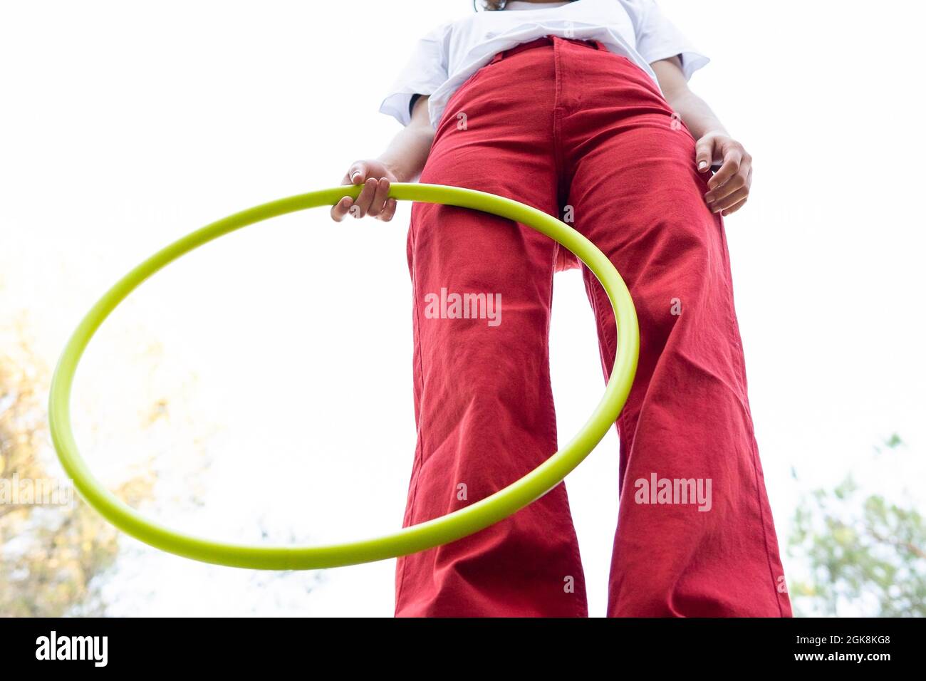 Von unten der Ernte unkenntlich weibliche Teenager in roten Jeans halten Hula Hoop Reifen während mit Freizeit im Park Stockfoto