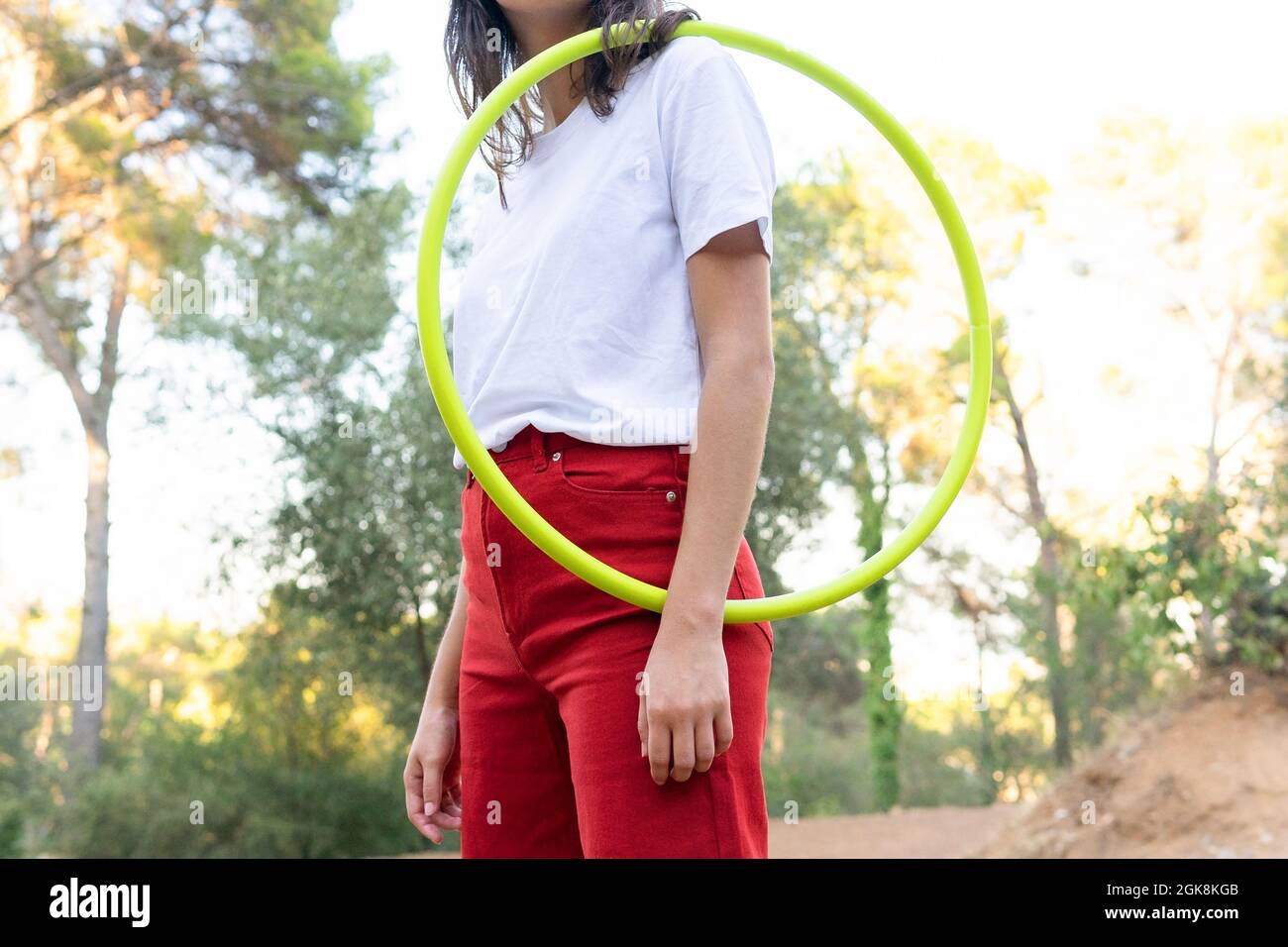 Crop unkenntlich weibliche Teenager in roten Jeans mit Hula Hoop halten, während Freizeit im Park Stockfoto