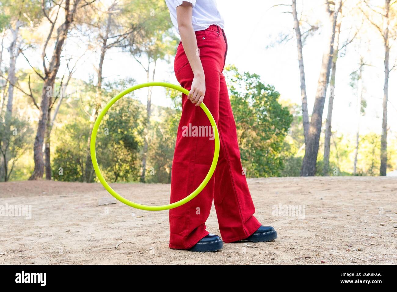 Seitenansicht der Ernte unkenntlich weibliche Teenager in roten Jeans halten Hula Hoop Reifen während mit Freizeit im Park Stockfoto