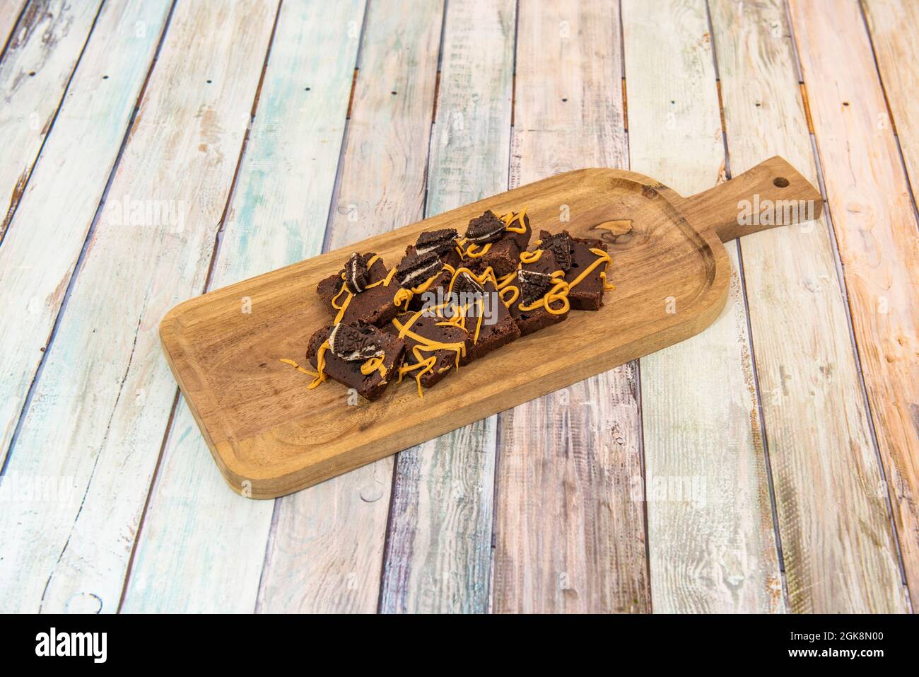 Tisch gefüllt mit rechteckigen Portionen von köstlichem Brownie mit Keksen, die in Schokoladencreme getaucht sind Stockfoto