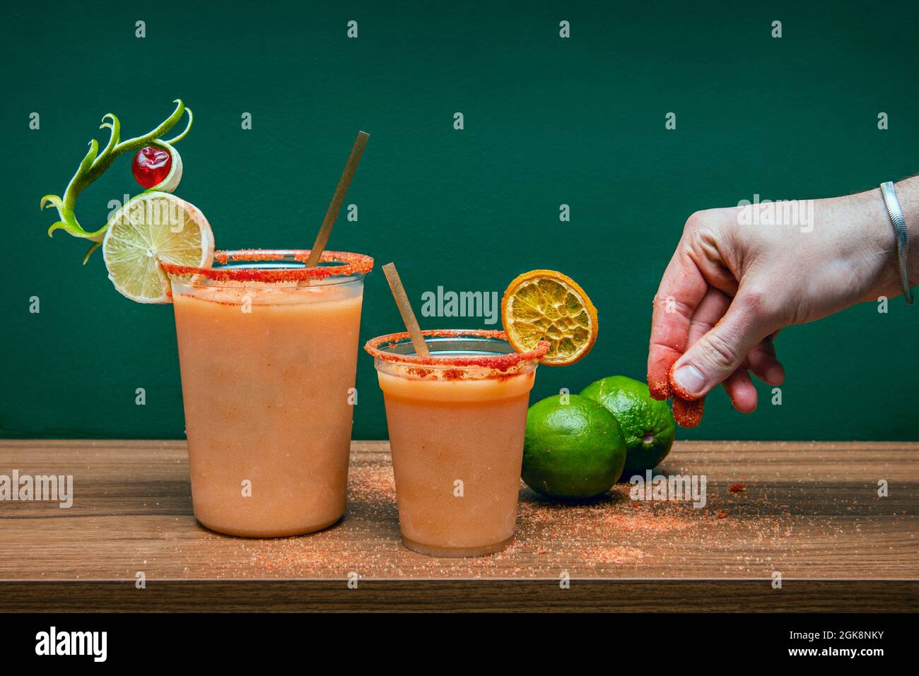 Mexikanischer Vampir-Cocktail in Plastikbechern mit Männerhand-Dressing die Getränke sind Salz und Gewürze, Limette, Zitrone und Orange Stockfoto