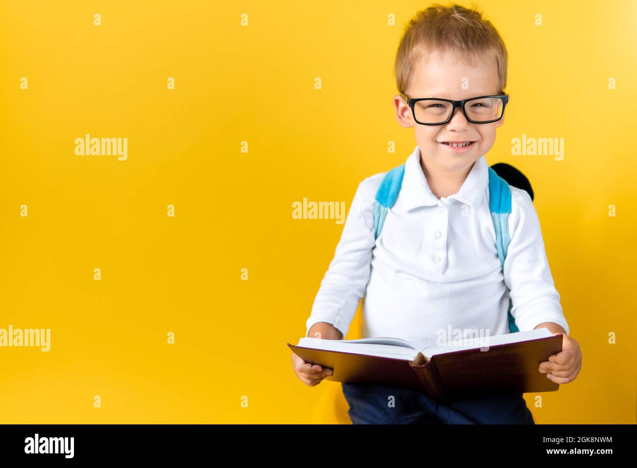 Banner Lustige Vorschule Kind Junge in großen Gläsern liest Buch auf gelbem Hintergrund Copy Space. Happy Smiling Kid Gehen Sie zurück zur Schule, Kindergarten. Erfolg Stockfoto