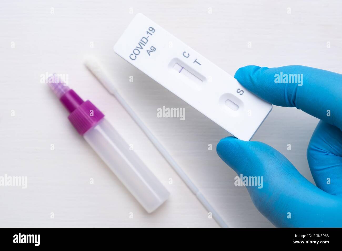 Negativer Coronavirus-Antigentest und Kit für die schnelle Diagnose in der Hand des Arztes in Gummihandschuhen auf weißem Hintergrund Stockfoto