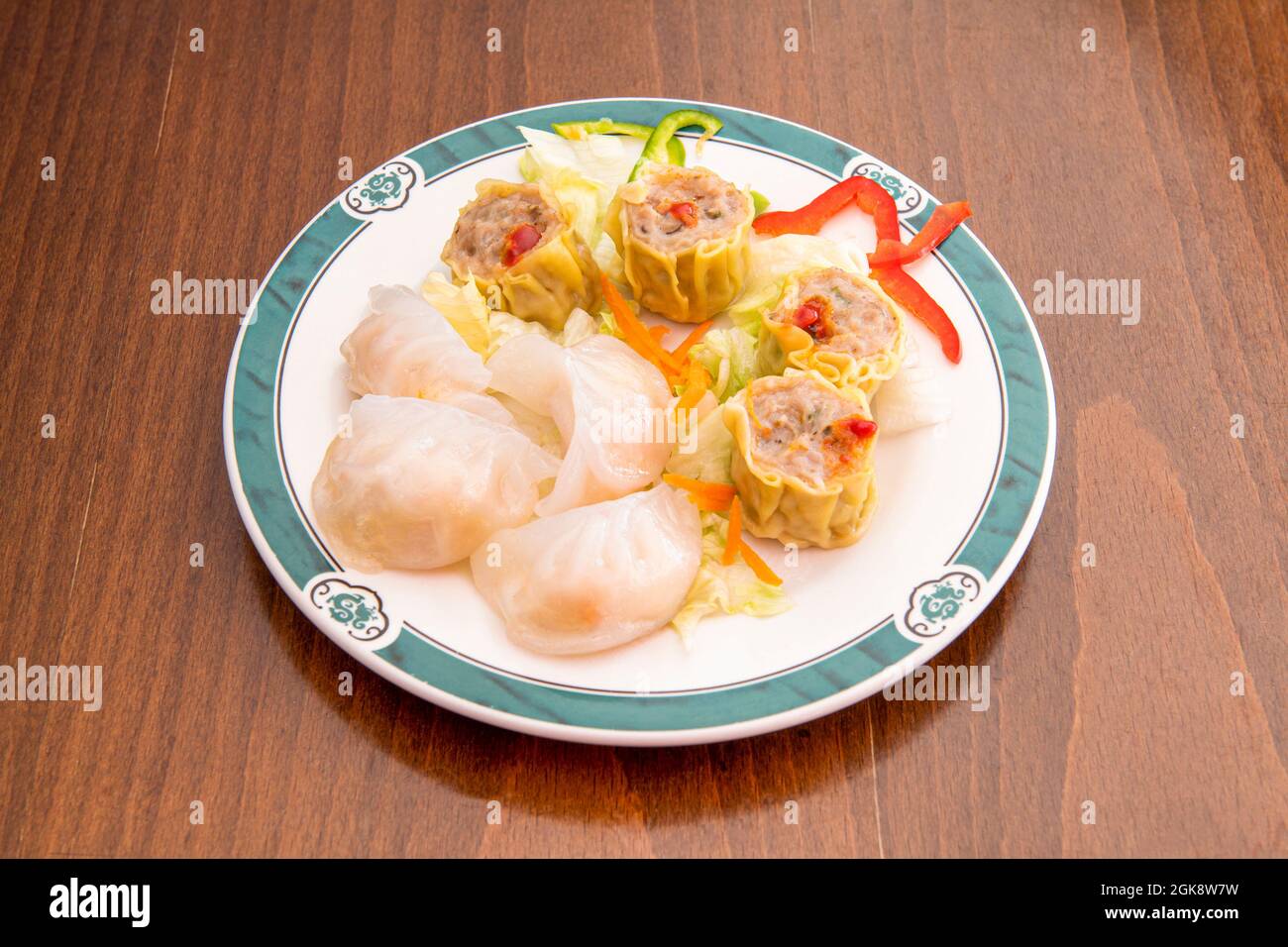 Verschiedene gefüllte chinesische Dim Sum-Gerichte mit Garnelen, Schweinefleisch und Gemüse auf einem Holztisch Stockfoto