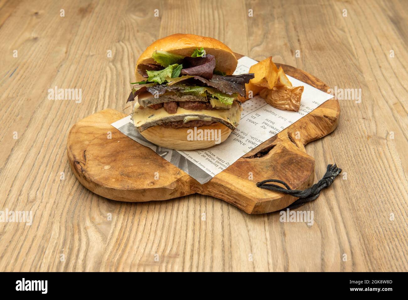 Rinderburger mit doppeltem Gras und doppeltem Bergkäse mit Waldsalat und einer Seite Pommes Frites Stockfoto