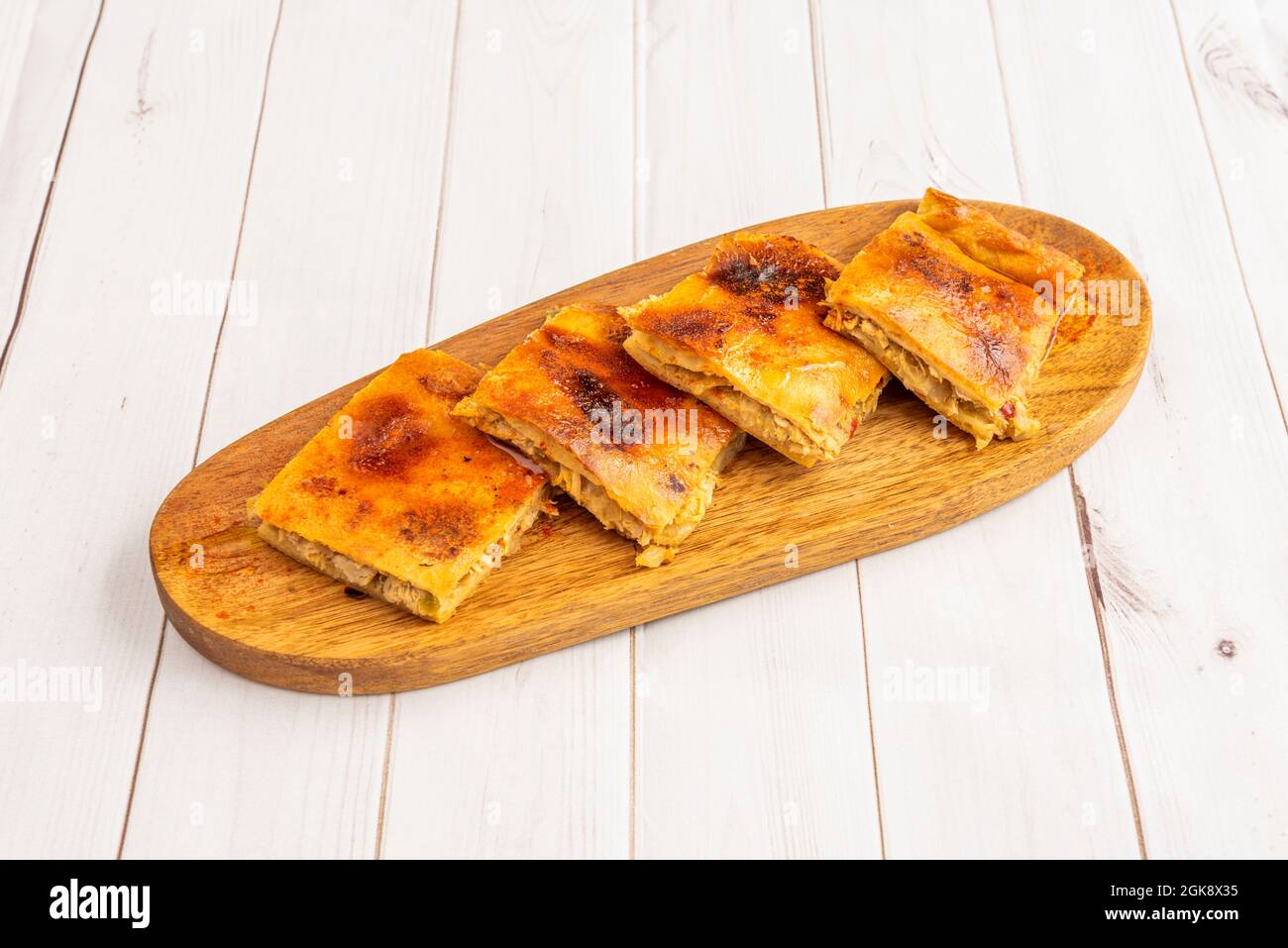 Stücke galicischer Empanada in Quadrate geschnitten, gefüllt mit Thunfisch-Eintopf, der mit Paprika bestreut ist Stockfoto