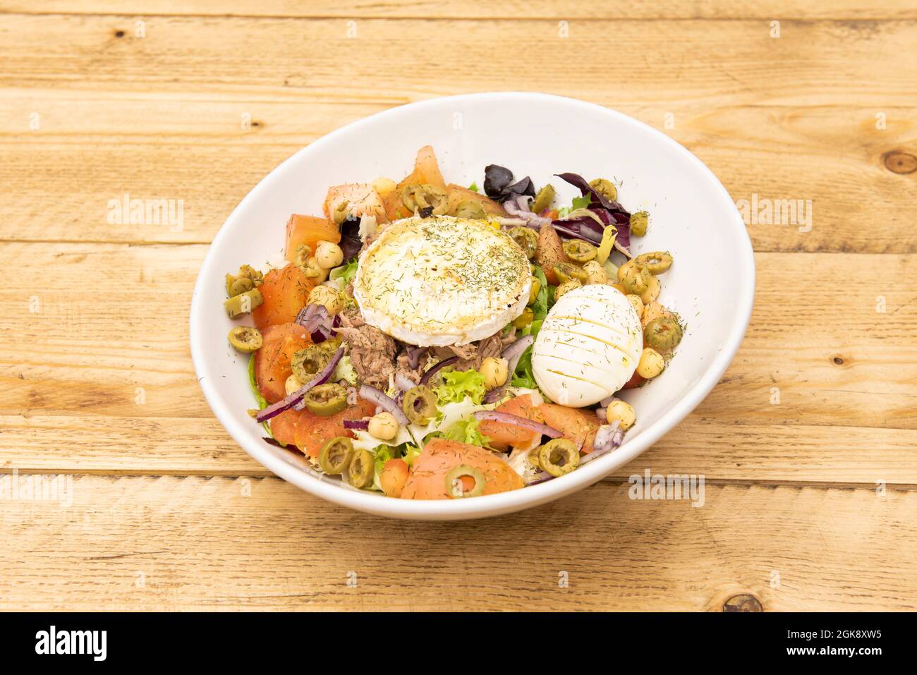 Toller mediterraner Salat mit vielen Gewürzen. Laminierte gekochte Eier, Thunfisch aus der Dose, Ziegenkäse, Stücke von grünen Oliven, gekochte Kichererbsen, gehackte t Stockfoto