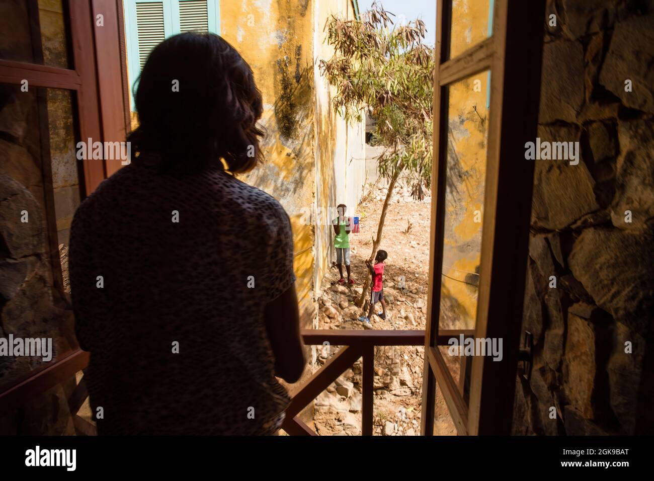 First Lady Michelle Obama blickt aus einem Fenster auf lokale Kinder während ihres Besuchs in einem Kulturzentrum auf der Insel Gorée, Senegal, 27. Juni 2013. (Offizielles Foto des Weißen Hauses von Chuck Kennedy) Dieses offizielle Foto des Weißen Hauses wird nur zur Veröffentlichung durch Nachrichtenorganisationen und/oder zum persönlichen Druck durch die Betreffenden des Fotos zur Verfügung gestellt. Das Foto darf in keiner Weise manipuliert werden und darf nicht in kommerziellen oder politischen Materialien, Anzeigen, E-Mails, Produkten, Werbeaktionen verwendet werden, die in irgendeiner Weise die Zustimmung oder Billigung des Präsidenten, der ersten Familie, Stockfoto