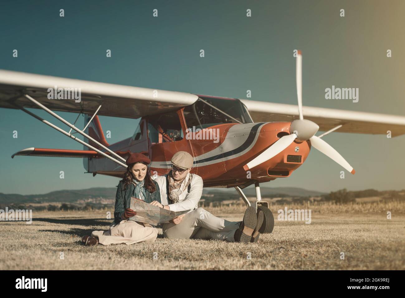 Junge Liebhaber, die auf der Karte in der Nähe ihres privaten Kleinflugzeugs, nobles Tourismus-Konzept Stockfoto