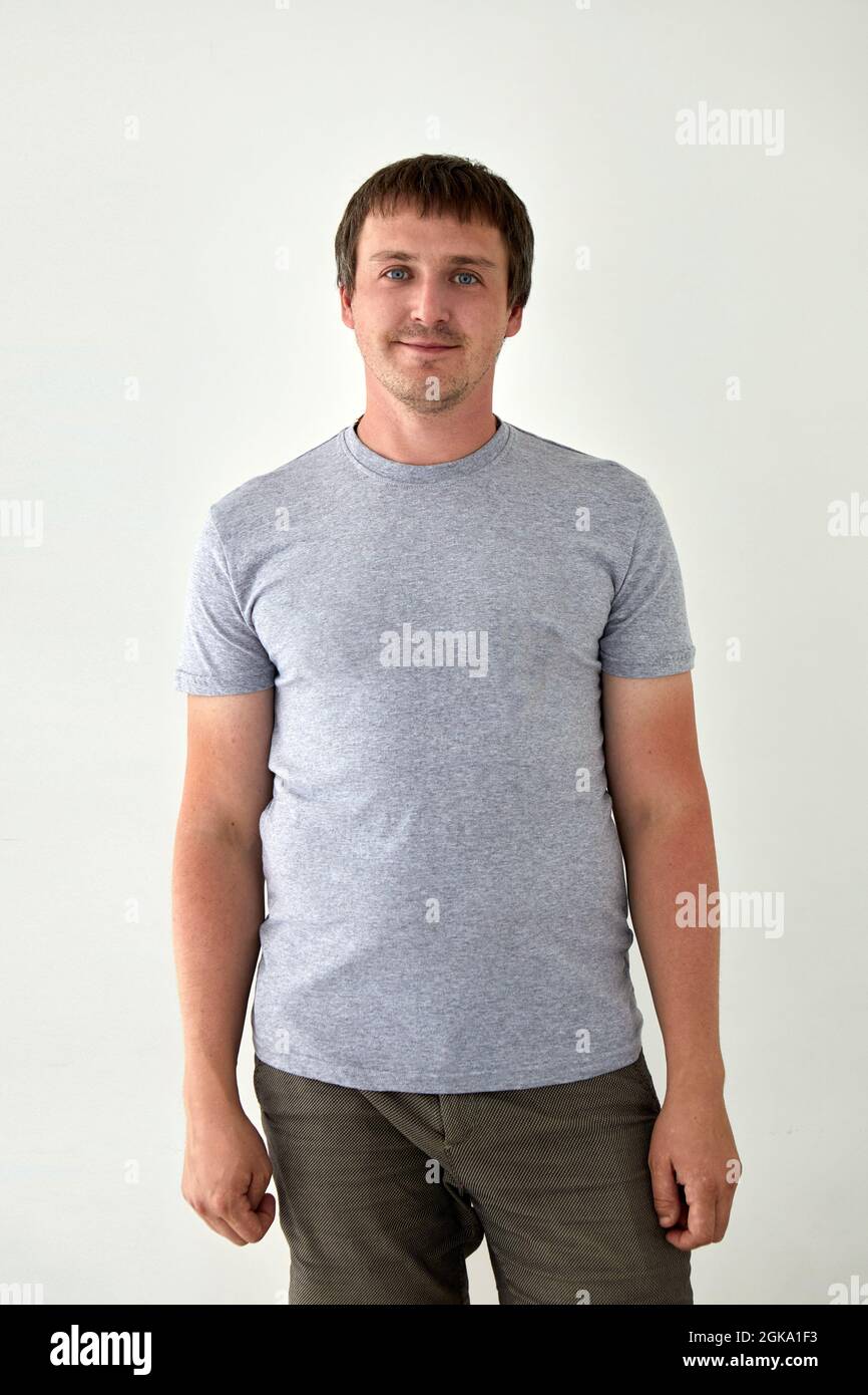 Inhalt Erwachsener Mann trägt graues T-Shirt auf weißem Hintergrund im Studio und Blick auf die Kamera Stockfoto