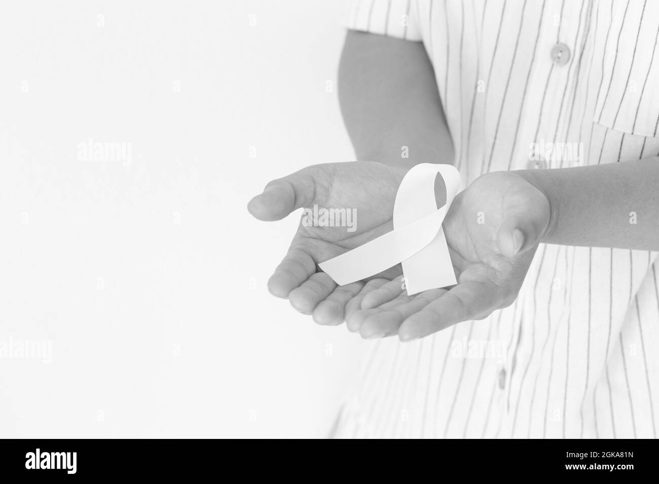 Hände halten weiße Perle Band Schleife auf weißem Hintergrund, kopieren Raum. Lungenkrebs Bewusstsein, Mesotheliom und Retinoblastom Krebs Symbol. Reinheit SIG Stockfoto