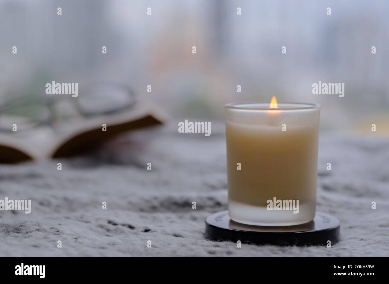 Brennende Flamme bei verschwommener Duftkerze zum Entspannen beim Lesen von Büchern zu Hause in der Wintersaison. Zen- und Relax-Konzept. Stockfoto