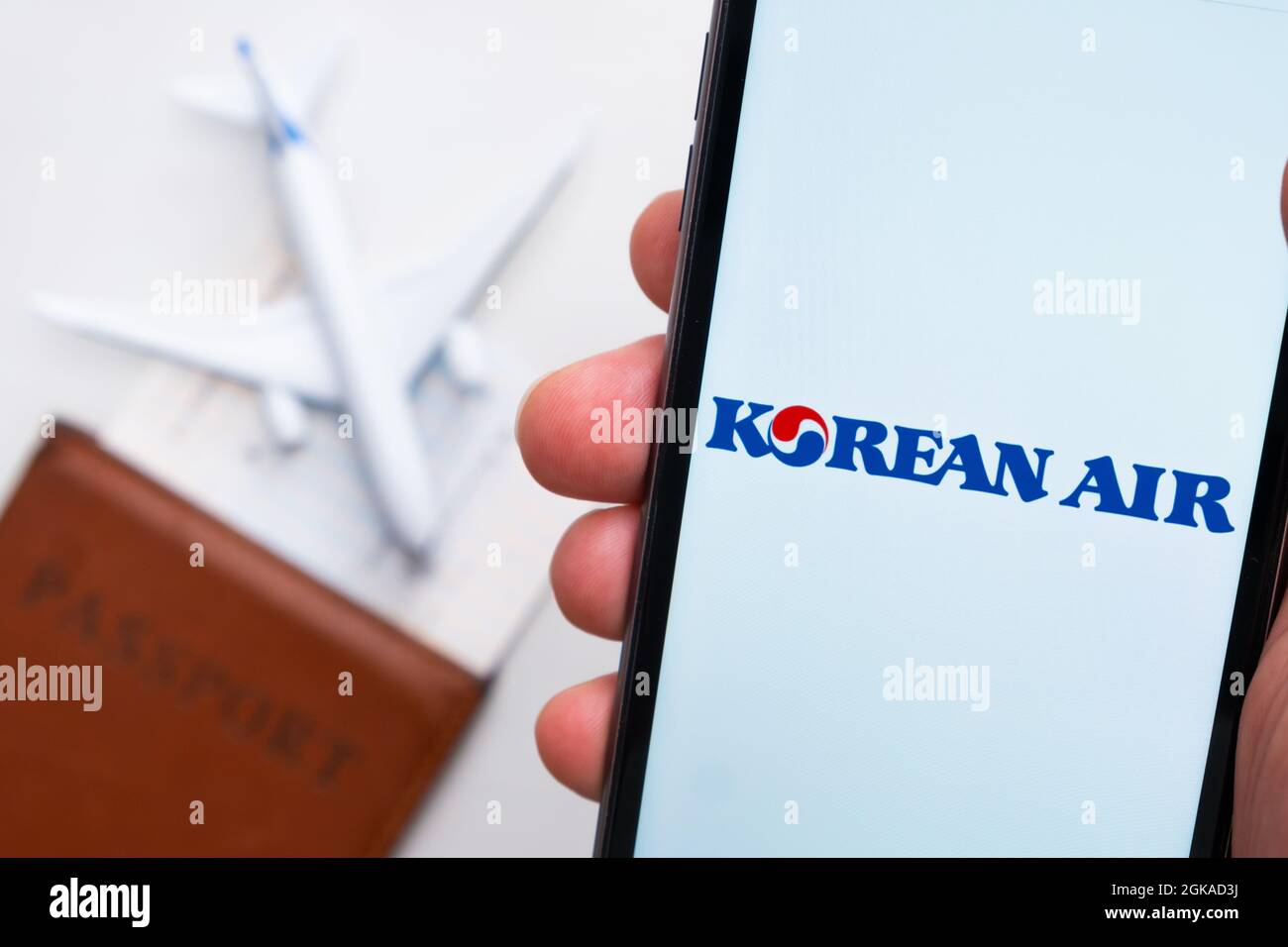 App oder Logo der koreanischen Fluggesellschaft auf einem Mobiltelefon mit Reisepass, Bordkarte und Flugzeug im Hintergrund, September 2021, San Francisco Stockfoto
