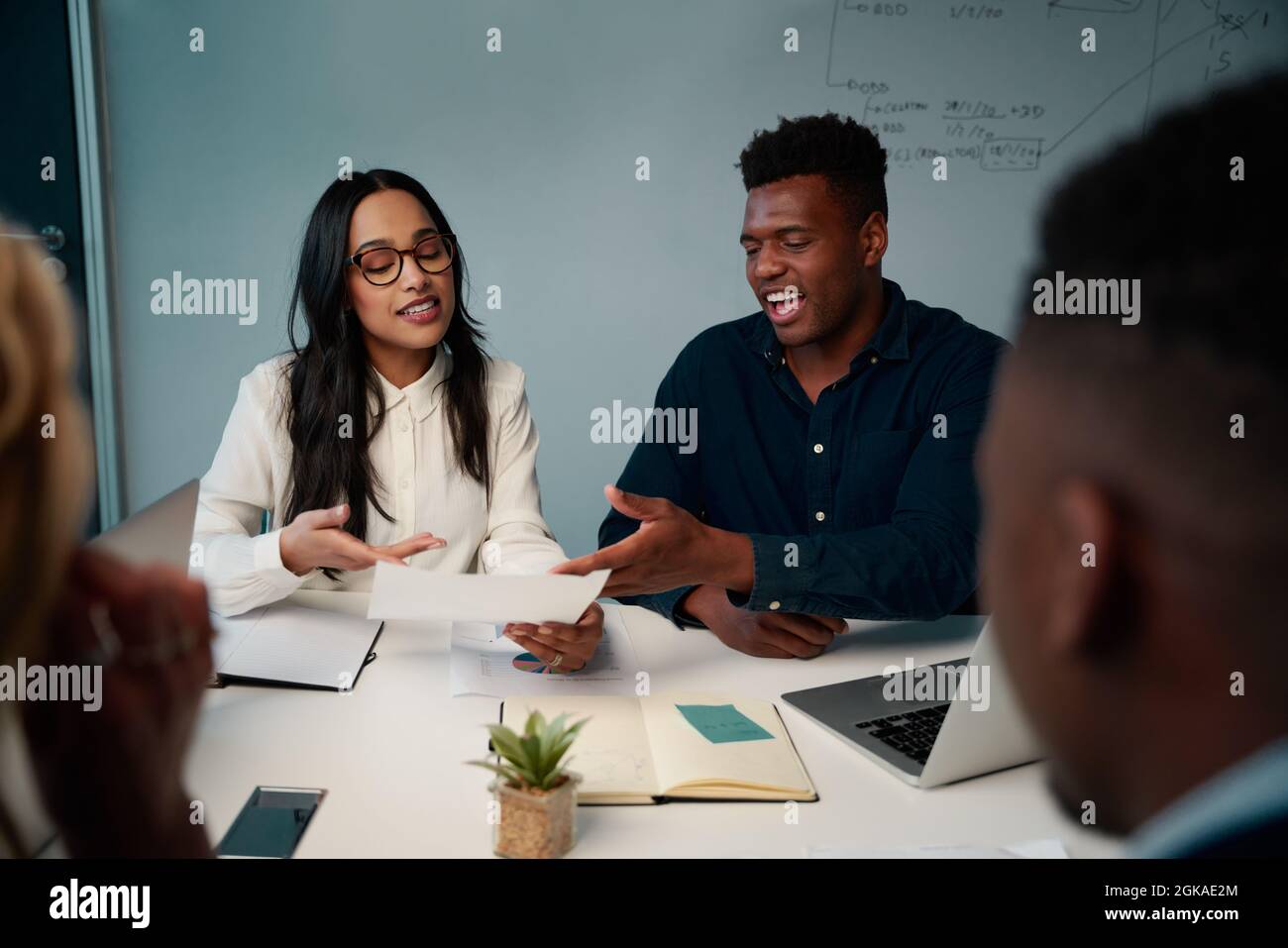 Multiethnischer junger Mann und Frau, die sich am Schreibtisch treffen und das Projekt im Büro besprechen Stockfoto
