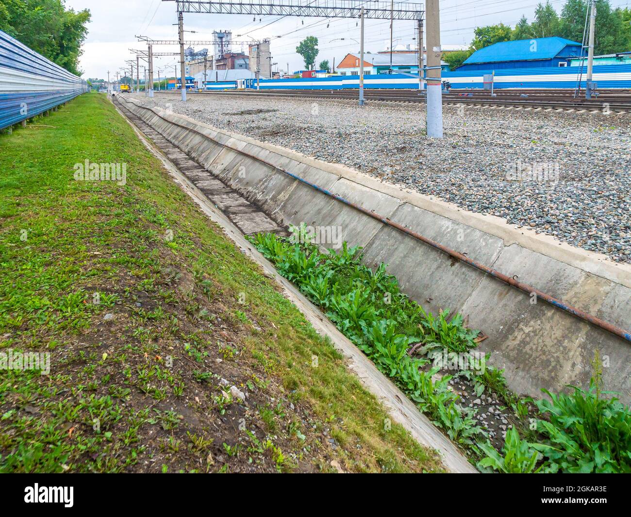 Ein mit Gras bewachsener Entwässerungskanal an einem Bahnhof wurde teilweise freigeräumt, selektiver Fokus Stockfoto