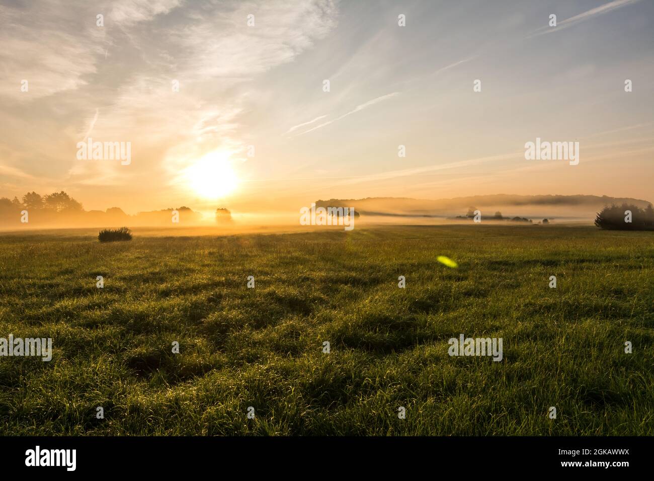 Schöner Sonnenuntergang in ländlicher Landschaft mit Sonnenstrahlen, die durch den Morgennebel scheinen Stockfoto