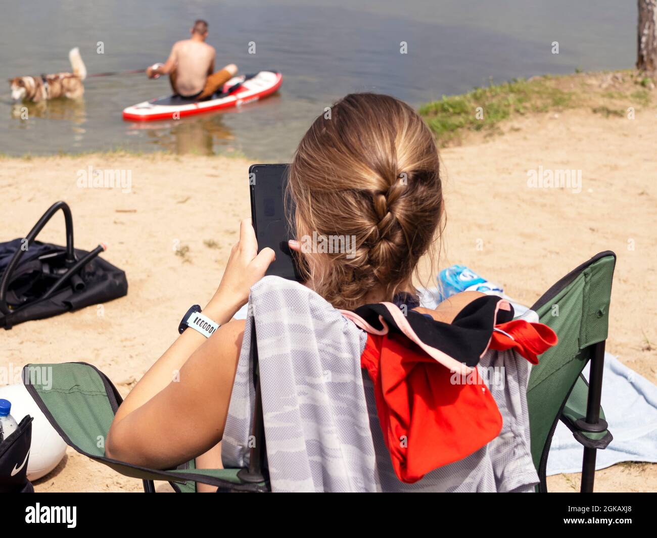 Nass Husky Hund und Spray von Wasser. Ein schöner Husky schwimmend im See. Hund steht auf dem SUP-Brett. Sommerzeit- und Urlaubskonzept. Platz kopieren. Stockfoto