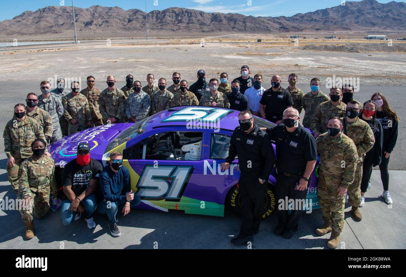 Service-Mitglieder und Mitglieder der Rick Ware Racing-Gruppe machen ein Foto über das Auto der Nummer 51 auf dem Luftwaffenstützpunkt Nellis, Nevada, 2. März 2021. Die Rick Ware Racing Group besichtigte vor dem kommenden Rennwochenende einige der Nellis AFB-Einrichtungen. Stockfoto