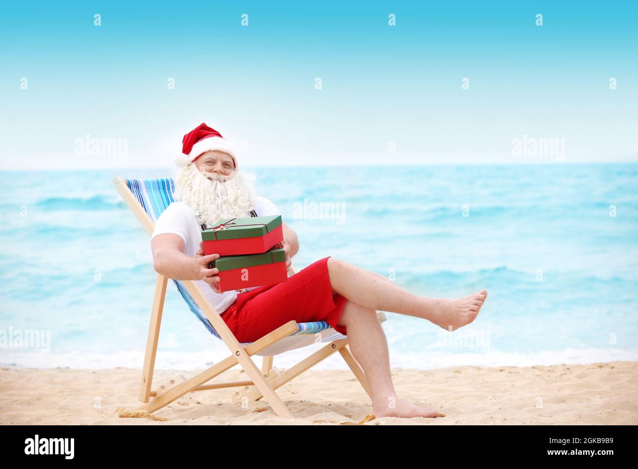Authentischer Weihnachtsmann mit Geschenkboxen im Liegestuhl am Strand  Stockfotografie - Alamy