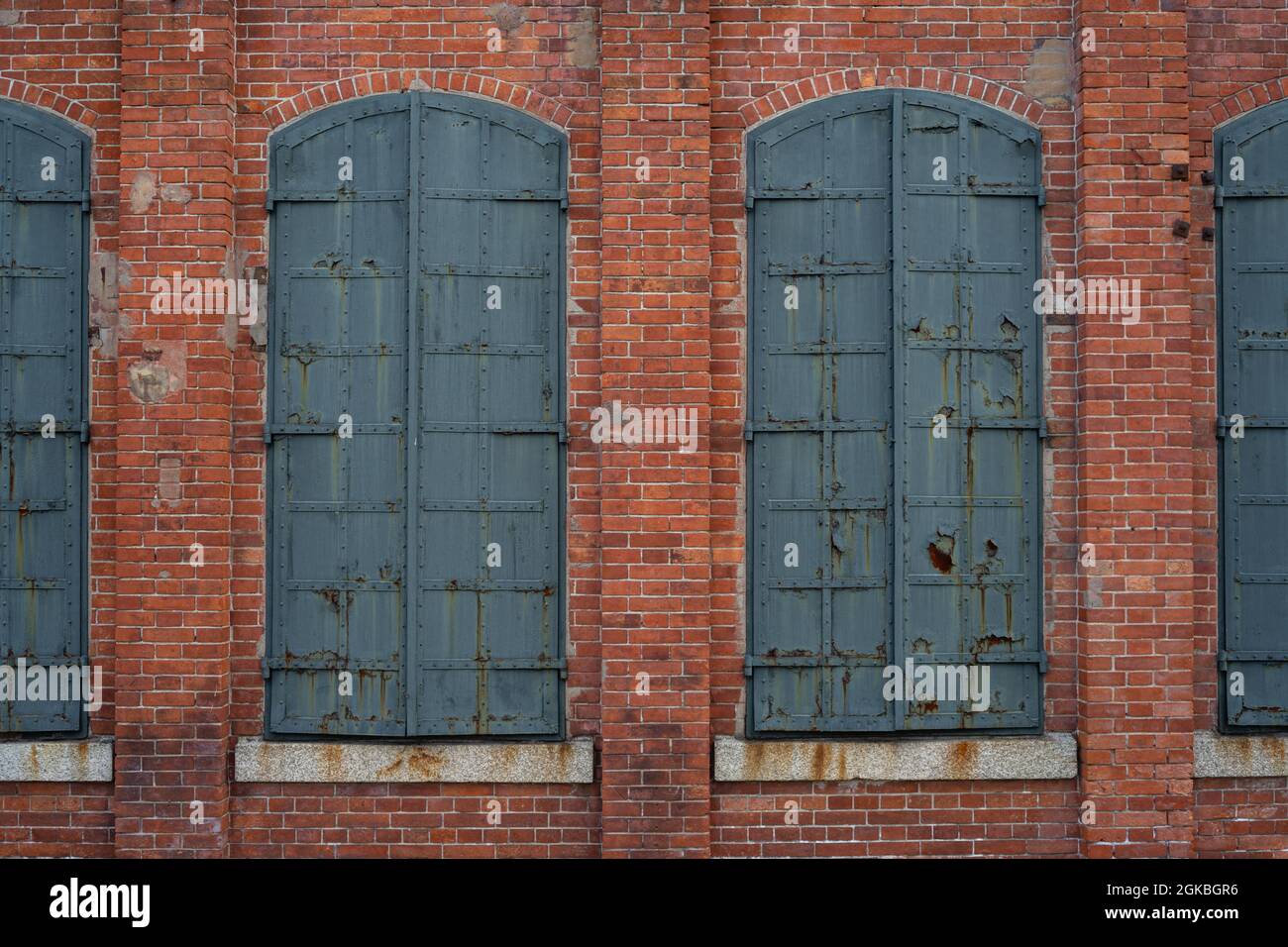 Geschlossene Fensterläden aus Eisen in einem historischen roten Backsteingebäude. Stockfoto