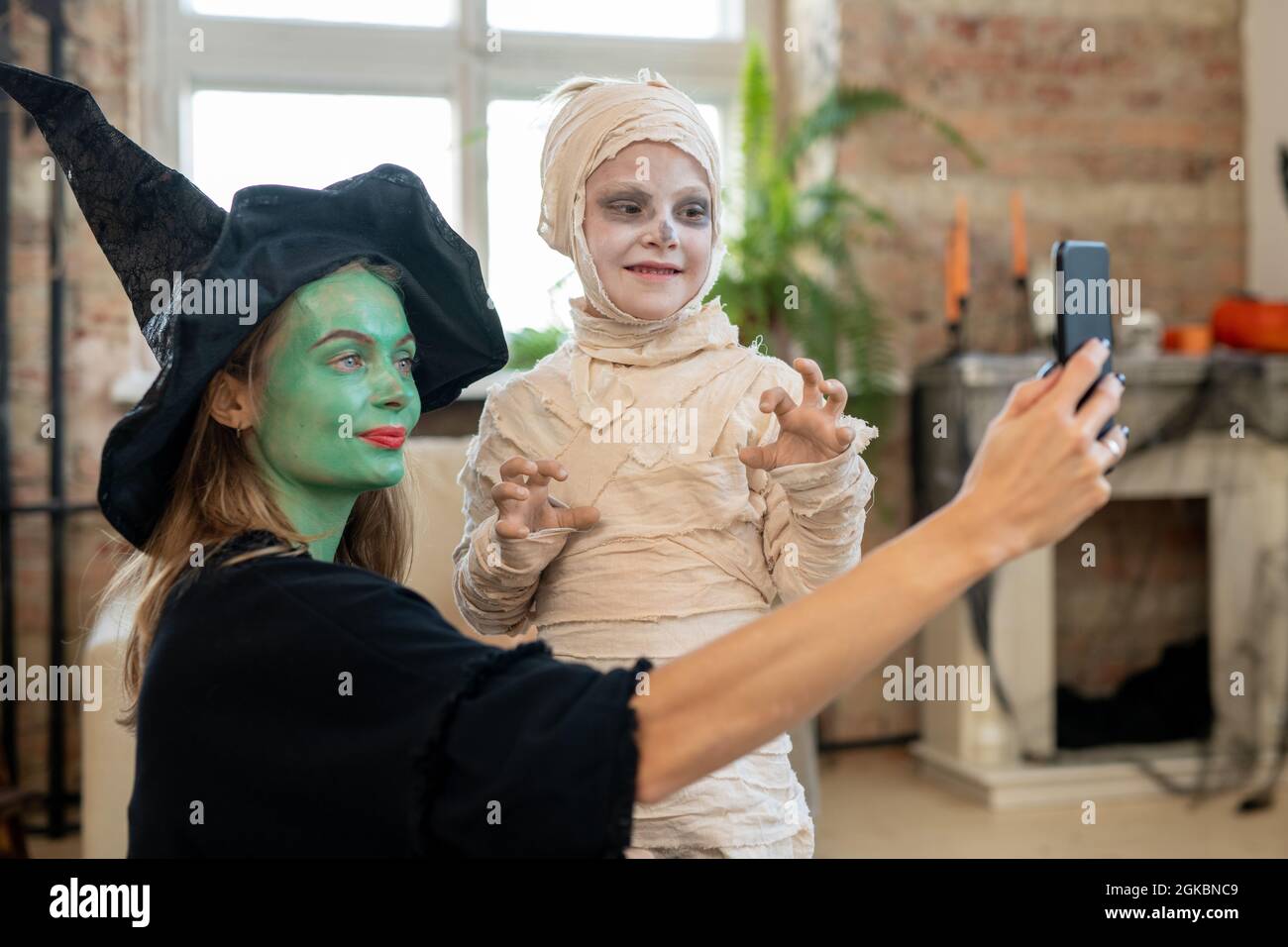 Mutter in Hexenkleidung macht am halloween-Tag Selfie mit ihrem Sohn im Zombie-Kostüm Stockfoto