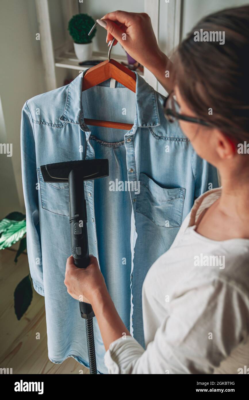 Frau dampft Dampfreiniger-Shirt in einem Raum zu Hause Stockfoto