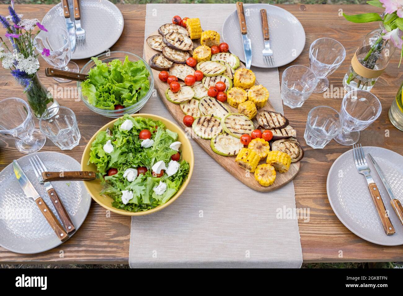 Serviert Tisch mit hausgemachten vegetarischen Speisen, Gläser und Teller zum Abendessen vorbereitet Stockfoto