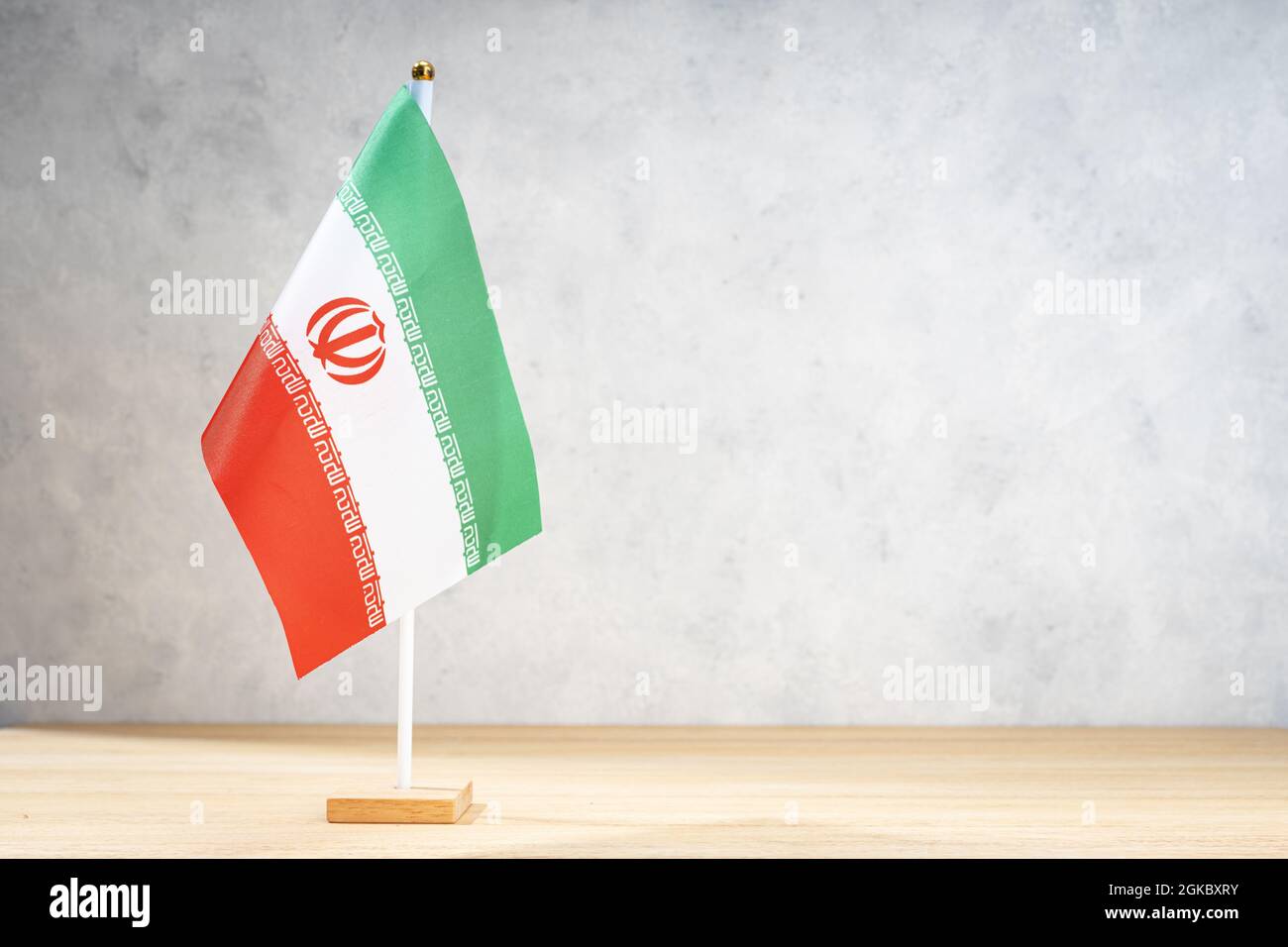 Iran Tischflagge auf weißer strukturierter Wand. Platz für Text, Entwürfe oder Zeichnungen kopieren Stockfoto