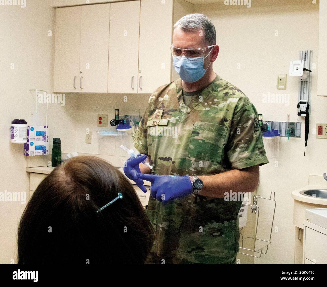 US Air Force Chief Master Sgt. Jody Nitz, ein kardio-pulmonaler Laborant, beauftragt mit der Task Force Bronco der Michigan National Guard (MING) COVID-19 Impftests, gibt den COVID-19-Impfstoff an einen Muskegon-Bewohner in einer Klinik auf dem Mercy Health Urgent Care Hackley Campus in Muskegon, Michigan, 9. März 2021. Der MING wurde gebeten, das Muskegon Gesundheitsministerium zu erweitern, um den Einwohnern des Bezirks Impfstoffe zu verabreichen. Stockfoto