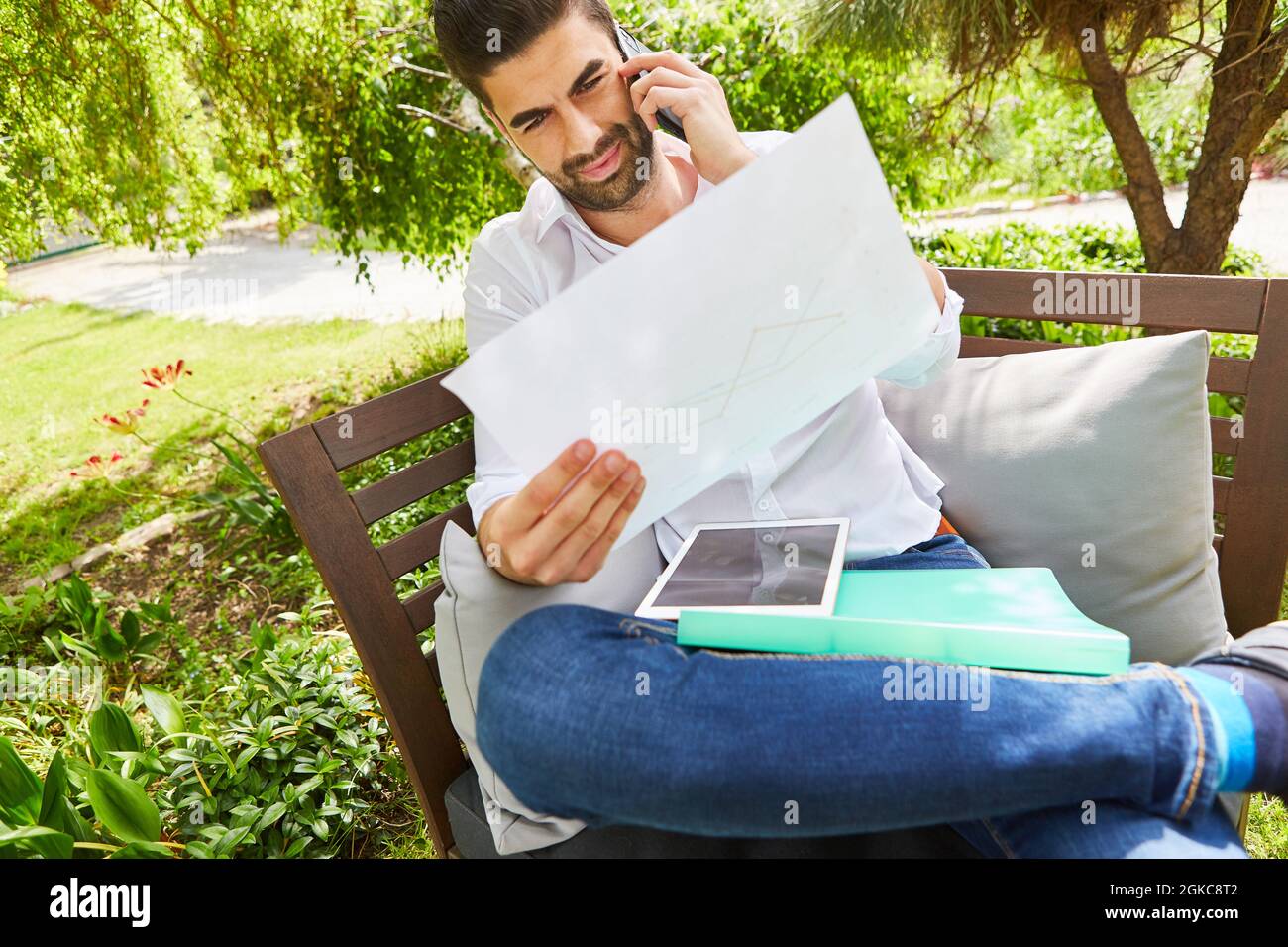 Freiberuflicher Mann, der im Sommer im Urlaub mit dem Handy im Garten telefoniert Stockfoto