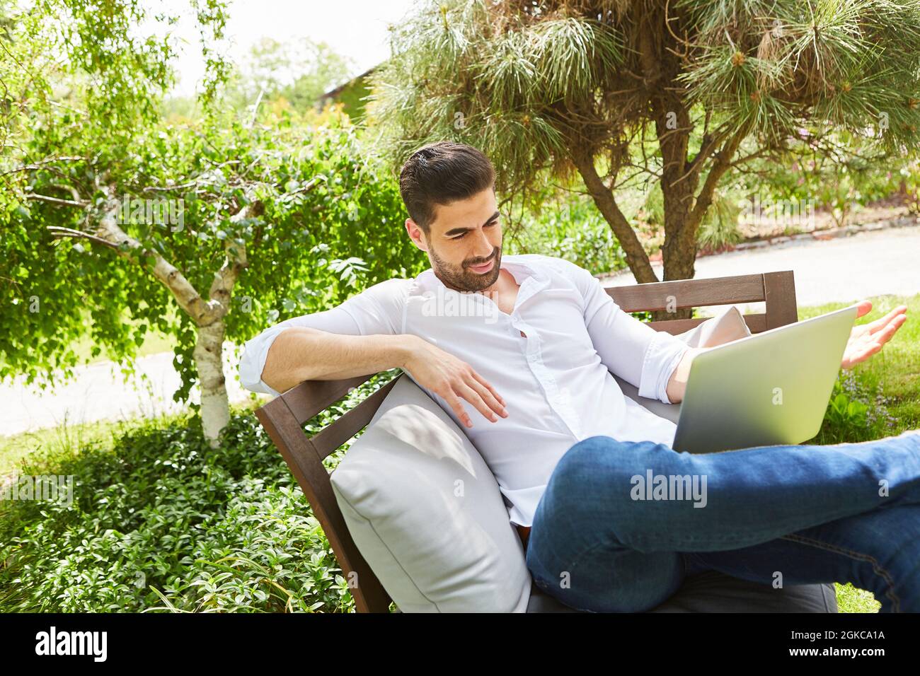 Casual man als Influencer auf dem Laptop-Computer online in den Sommerferien im Garten Stockfoto