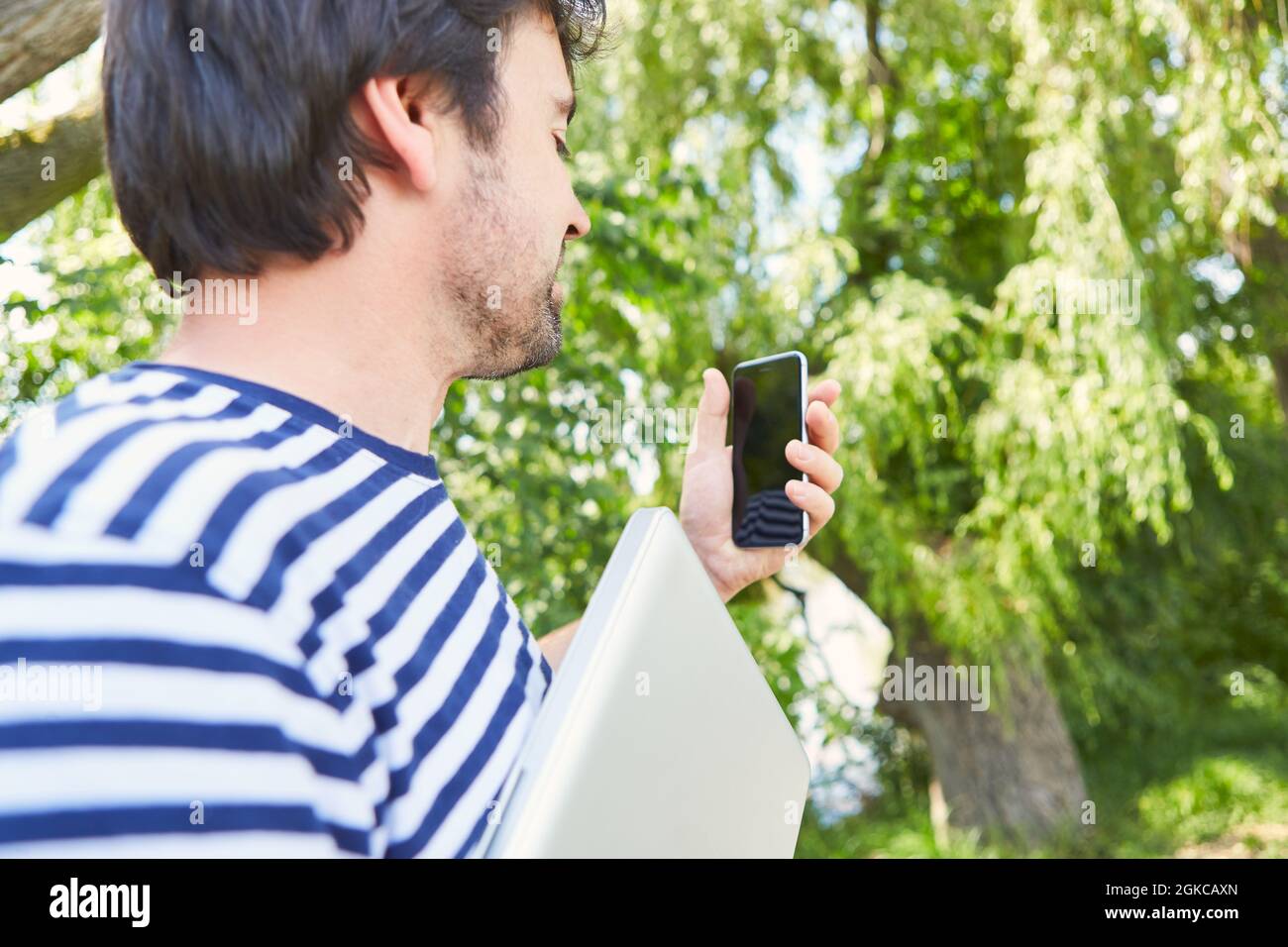 Im Sommer liest man als Freiberufler SMS-Nachrichten auf dem Smartphone in der Natur Stockfoto