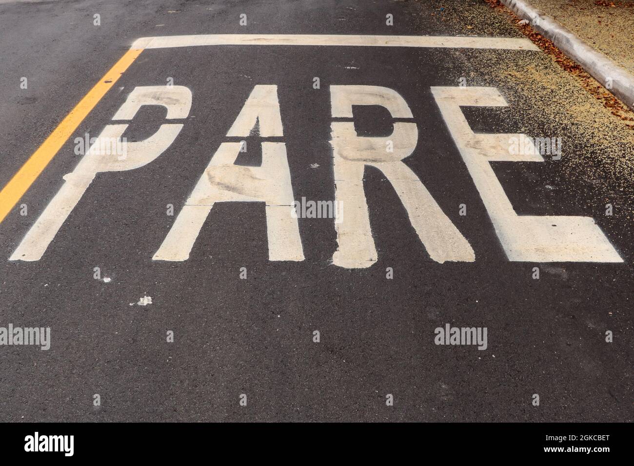 Asphaltweg frisch mit etwas Schmutz gemacht und in der oberen rechten Ecke der Pollen eines Baumes. Das Wort STOP ist auf dem Foto (auf Portugiesisch) Stockfoto