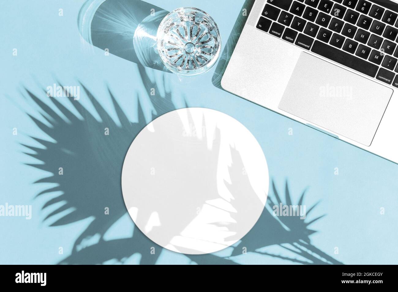 Laptop und rundes Mauspad mit Sonnenschatten. Arbeitsplatz flach liegend. Mouse Pad Mockup für Ihr Design Stockfoto