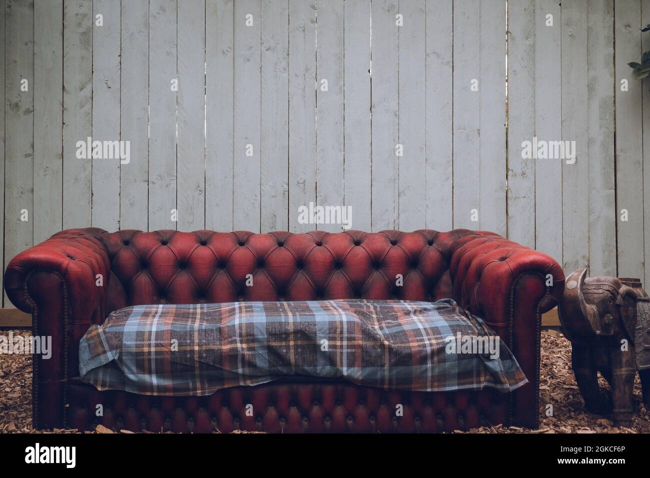 Ein rustikal aussehendes antikes Sofa vor einer verwitterten Holzwand Stockfoto