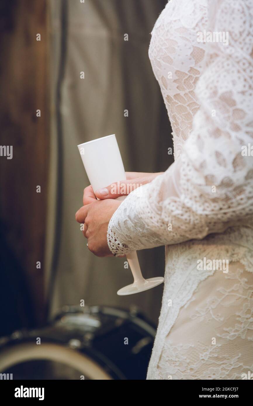 Eine Braut in einem Hochzeitskleid mit einer Sektflöte oder einem Weinglas Stockfoto