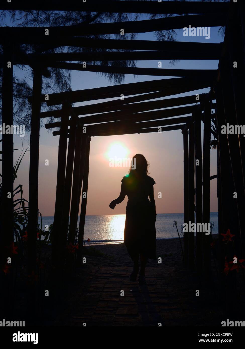 Eine Sonnenuntergangs-Silhouette stellt eine Frau am Strand dar Stockfoto