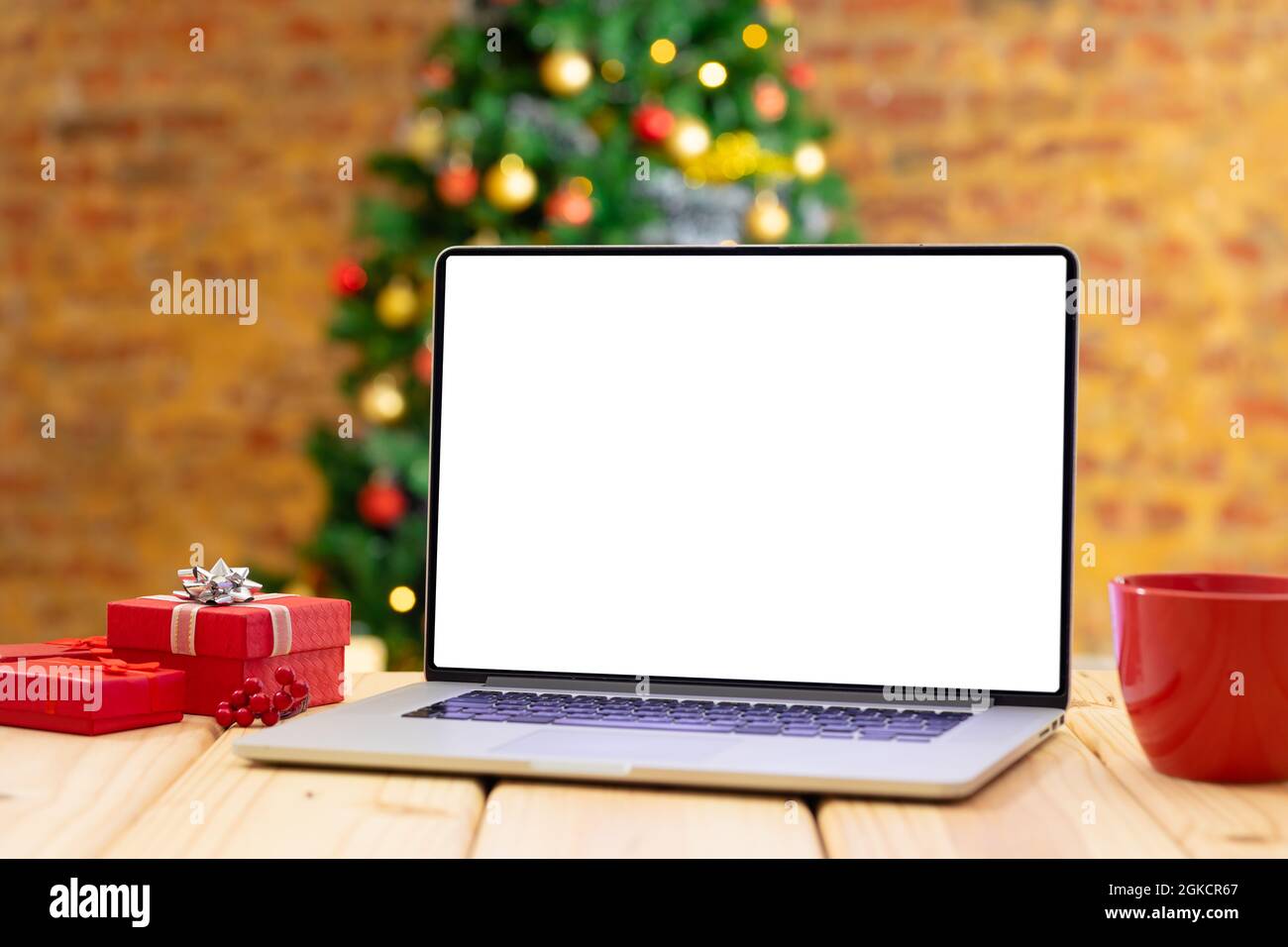 Komposition von Laptop mit Kopierplatz auf Holztisch mit weihnachtsbaum im Hintergrund Stockfoto