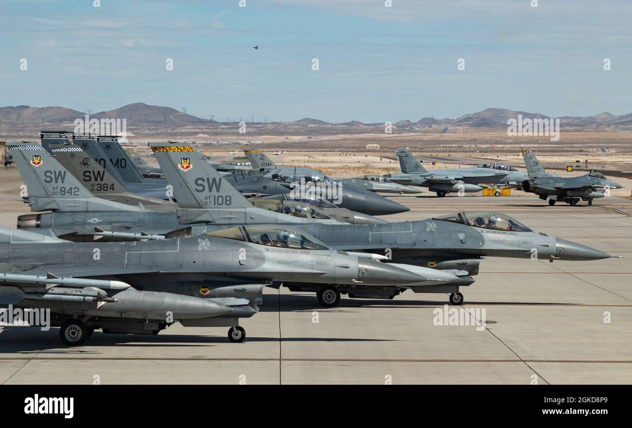 Mehrere F-16CM Falcon-Kampfflugzeuge, die dem 20th Fighter Wing, der Shaw Air Force Base, South Carolina, und den F-15SG Strike Eagles-Kampfflugzeugen, die dem 428th Fighter Squadron, Mountain Home AFB, Idaho, zugewiesen wurden, warten auf den Start für eine Mission der Roten Flagge 21-2 auf der Nellis AFB, Nevada, 18. März 2021. Red Flag findet über dem Nevada Test and Training Range statt und bietet dem Kriegsjäger einen flexiblen, realistischen und multidimensionalen Kampfraum, um eine erweiterte Ausbildung der US-Militärdienste und Koalitionstruppen durchzuführen. Stockfoto