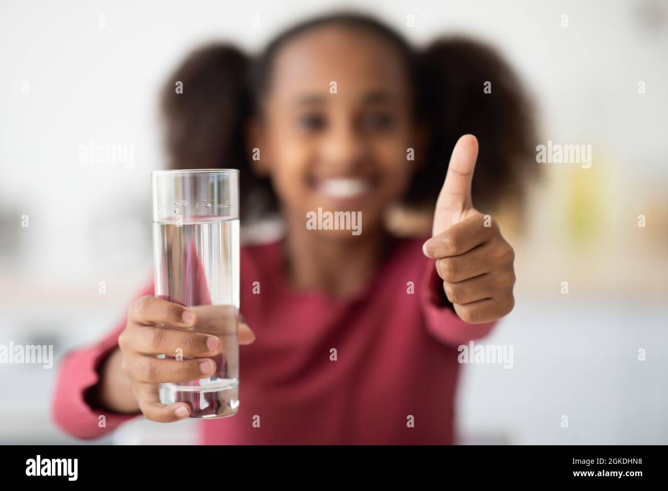 Glas Wasser und Daumen hoch, unbekanntes Mädchen trinkt Wasser Stockfoto