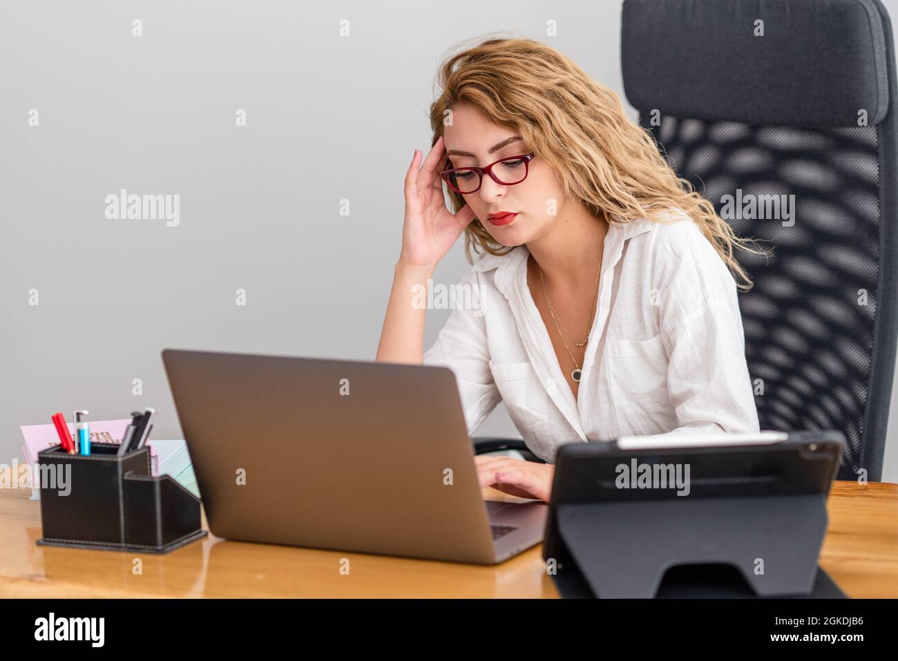 Die junge Frau arbeitet hart in ihrem Büro und beschäftigt sich mit Prblemen, mit moderner Ausrüstung. Hochwertige Fotos Stockfoto