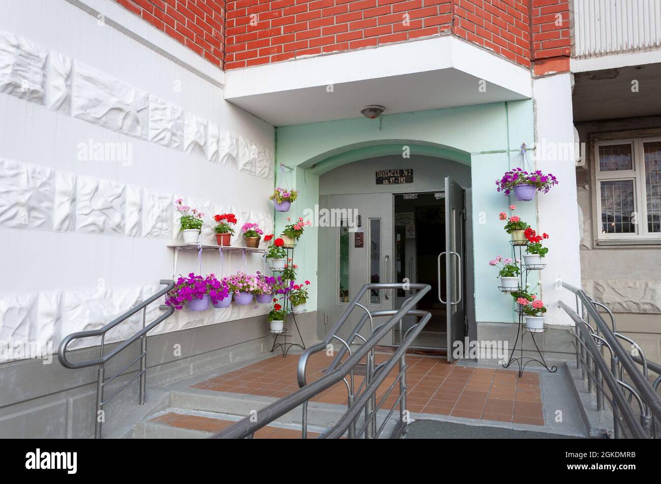 Krasnogorsk, Russland - Juli 22. 2021. Eingang zu einem mehrstöckigen Wohngebäude mit frischen Blumen Stockfoto